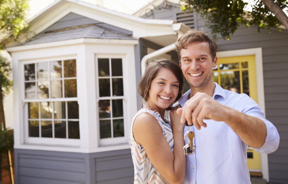 A couple holding keys and smiling in their new home